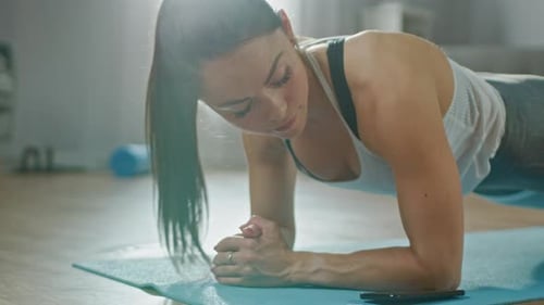 Focused woman doing plank exercise on yoga mat