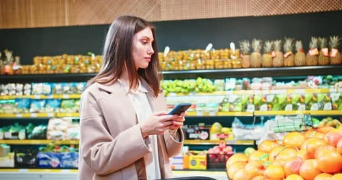 Successful Caucasian Lady Checking Her Shopping List on Smartphone in Grocery Store Young Woman