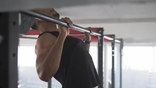 Exercising on pull-up bar, man doing pull-ups in gym