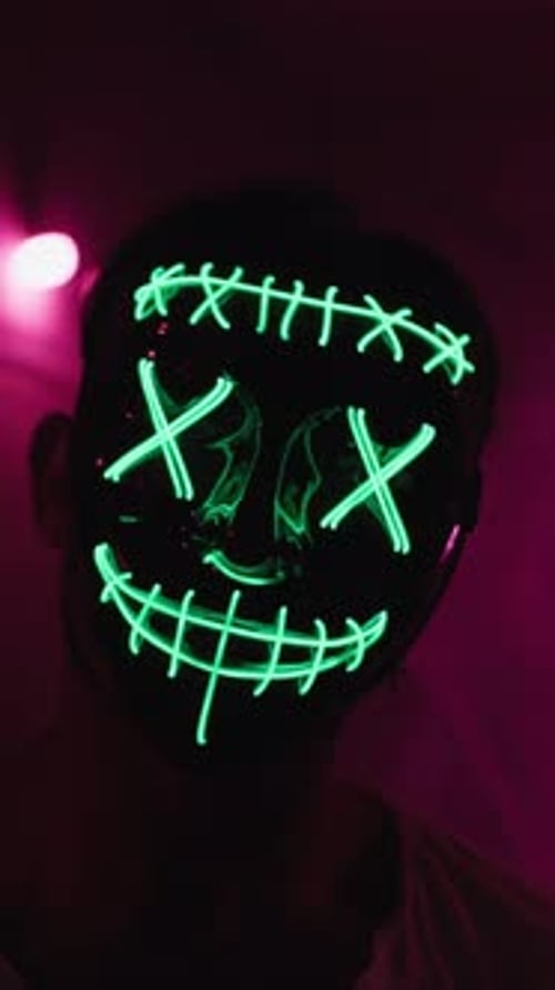 Person Wearing Glowing Neon Green Mask in Dark Room