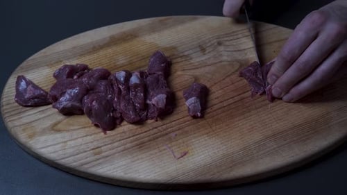 Man Slicing Fresh Beef Meat On Wooden Board - Close up