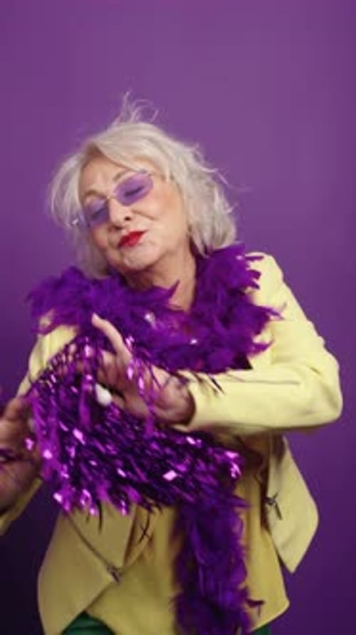 Happy Senior Woman Dancing With Purple Pompoms