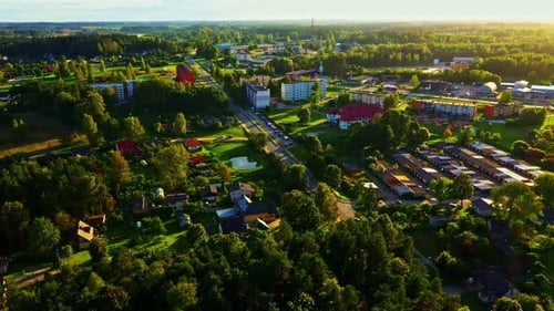 Wide aerial view of Smiltene town during warm sunset with buildings and trees in Latvia