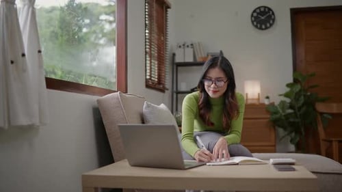 Woman wears green sweater working studying and liniving at home.