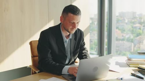 In a Modern Office Overlooking the Cityscape a Dedicated Businessman Focuses on Boosting