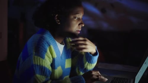 Side View Concentrated Young Latin Girl Using Laptop at Home Night Black Female People Illuminated