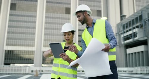 Two young engineers using a digital tablet while collaborating in the city