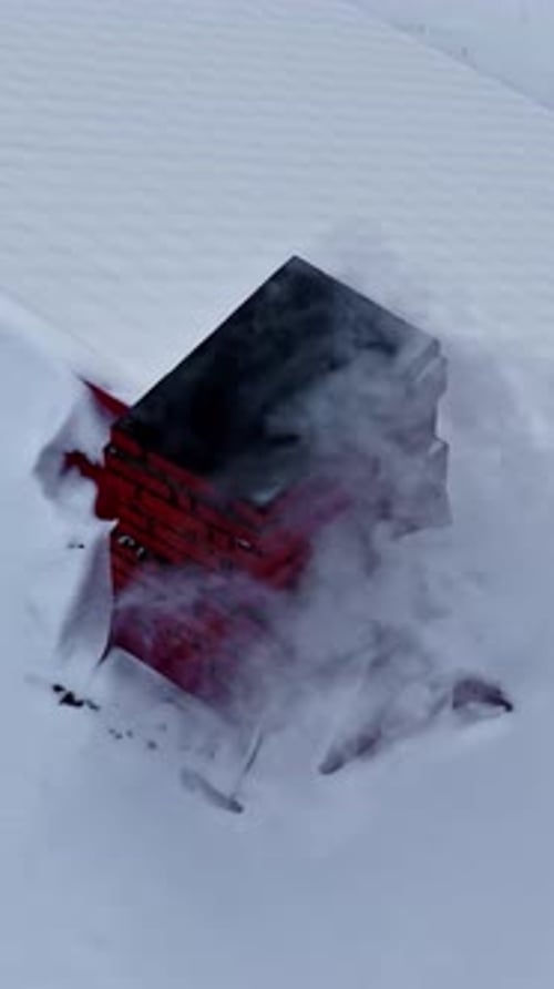Smoke Rising from Red Brick Chimney on Snow-Covered Roof
