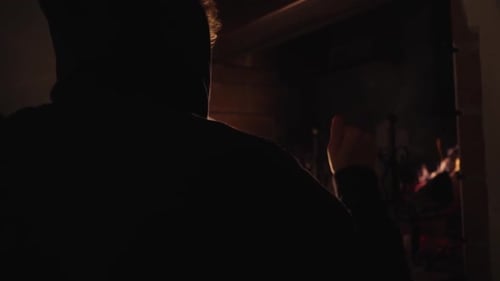 Silhouetted Figure Watching Fireplace Indoors