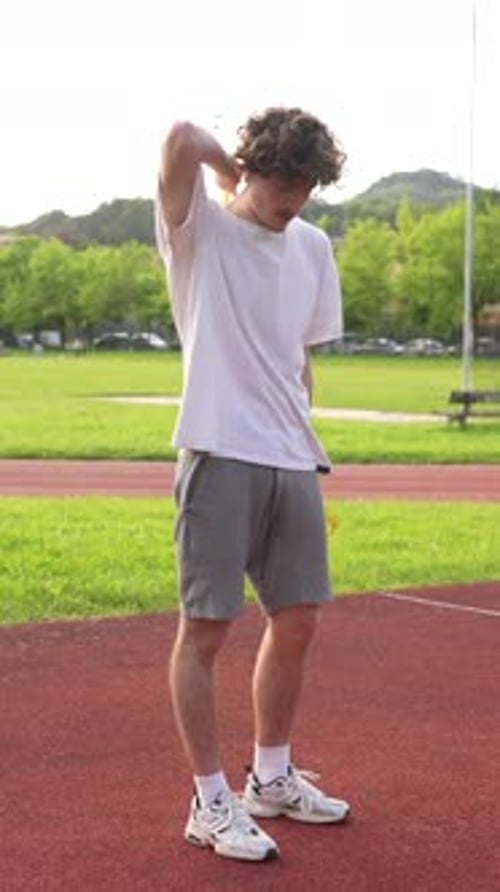 Young Man Stretching with Exercise Band on Running Track