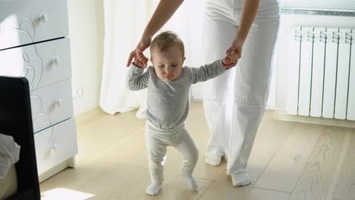 Adorable Infant Taking First Steps with Assistance