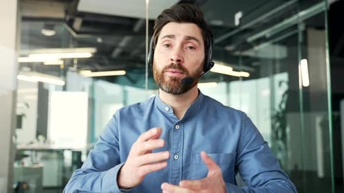 Webcam view. Confident businessman in headset talking on a video call looking at camera sitting