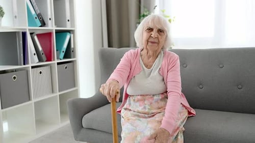Senior Woman Laughing on Couch with Cane