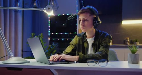 Handsome Caucasian Man Working on Laptop Computer while Sitting Behind Desk in Living Room.