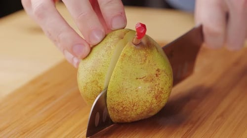 Chef Cuts Bio Green Pear with Knife on a Cutting Board to Make Dessert Compote or Fruit Juice