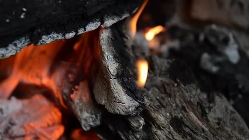 Nahaufnahme von Brennholz mit einer kleinen Flamme