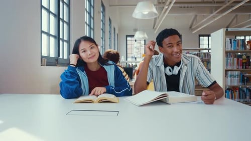 Young and cheerful multiethnic students in library