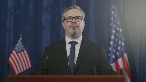 Man Giving Political Speech at Podium With Flags