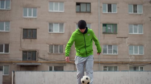 Teen Juggling Soccer Ball Skillfully in Urban Environment
