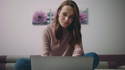 Woman Using Laptop on Sofa in Bright Room