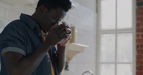 Young Man Enjoying Coffee in Bright Kitchen