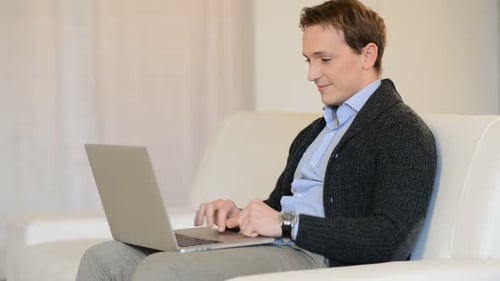 Man Works on Laptop While Sitting on Couch