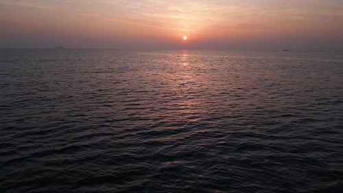 Aerial Drone View of a Serene Sunset Over the Calm Sea with Soft Pastel Colors Reflecting on the