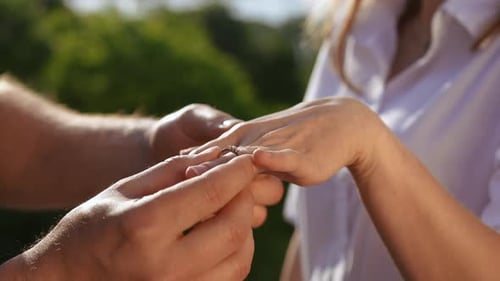 The Man Having Proposed Puts the Ring on the Finger of His Beloved Closeup Shooting Outdoors