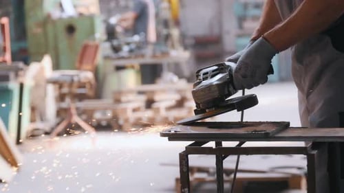 A worker at a heavy industry factory for the production of metal structures. A man in a uniform grin