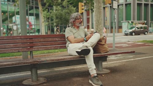 Relaxed Man Sitting on Park Bench Using Phone