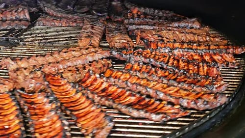 Gegrillte Rippchen auf einem großen Barbecue-Grill Mehrere Rippchen werden auf einem großen Barbecue-Grill gegrillt