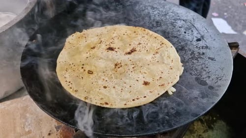 À Nehru Place, à Delhi, une paratha est en train de cuire sur une plaque chauffante avec de la vapeur qui monte.