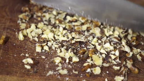 Closeup of knife chopping nuts.