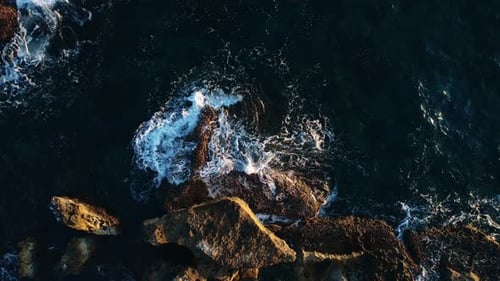 Aerial View on Dark Blue Waves Splashing on Rocks