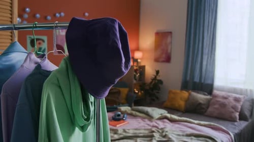 Étagère de fermeture avec chapeau seau violet, sweat à capuche vert et autres articles dans la chambre à coucher