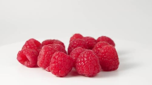 Raspberries rotate on a white background.