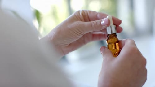 Woman Using Dropper with Glass Bottle