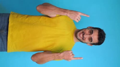 Happy Man with Yellow Shirt Pointing at Empty Space