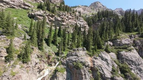 Waterfall Cascading Down Rocky Cliffs in a Lush Green Forest