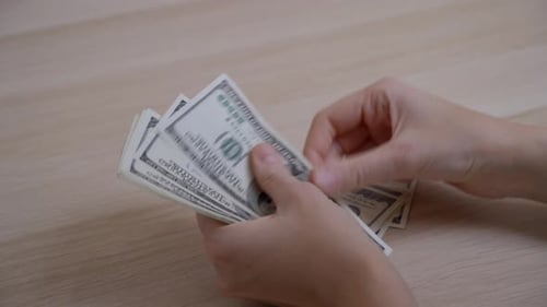 Hands Count Hundred Dollar Bills on Table