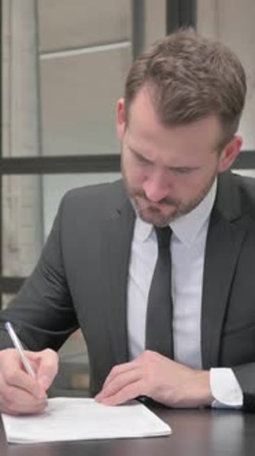 Man in Suit Signing Documents at Desk