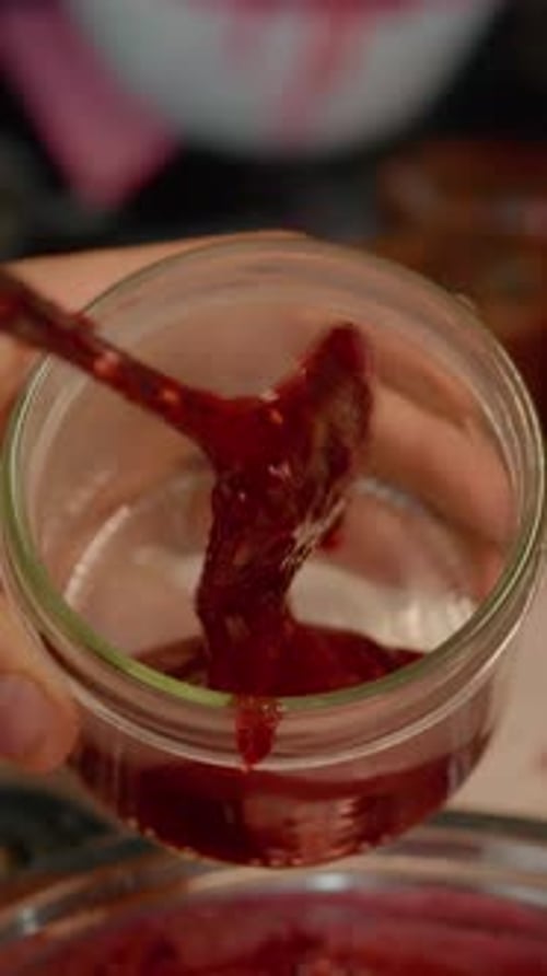 Filling Small Glass Jar with Sweet Red Jam