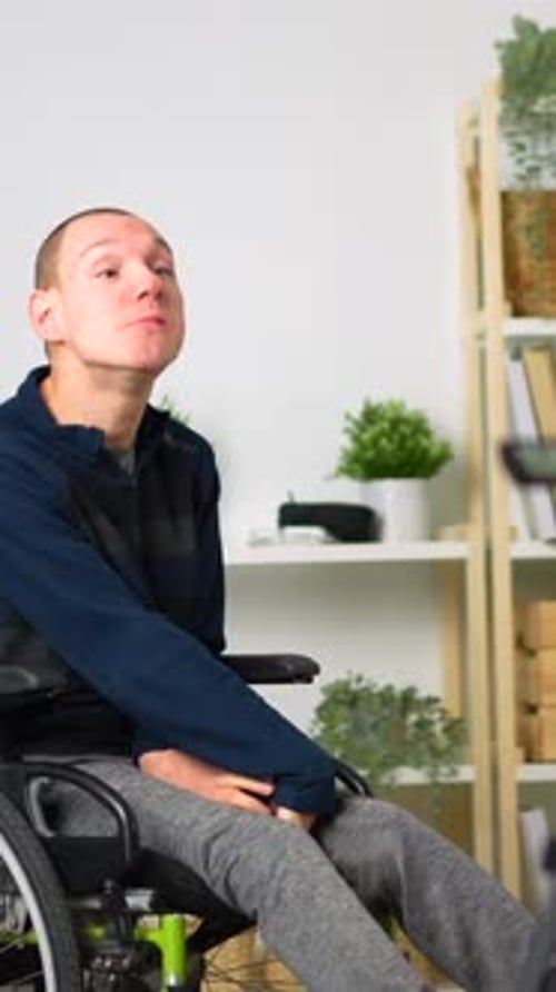 Young Man Communicates While Sitting in Wheelchair Indoors