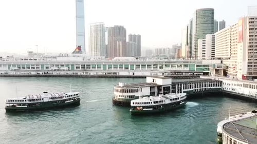Aerial panning shot of boats in sea by buildings against sky at sunset, drone flying over water by c