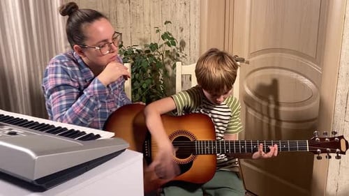 Child Learns Guitar From an Adult in Home