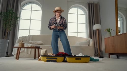 Woman Dances while Packing Suitcase for Travel