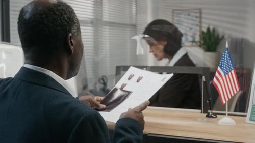 Female Visa Center Official Checking Identity of Black Male Applicant
