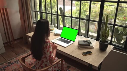 Woman Working on Laptop Computer or Looking at Online Video Call on Green Screen