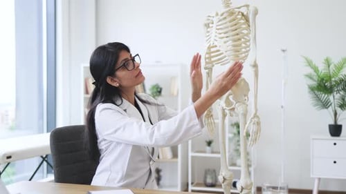 Hospital worker examining bones location on plastic skeleton