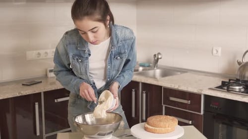 Pretty brunette with ponytail cooks in kitchen. She adds whole pack of butter into silver bowl befor